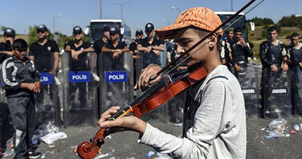 13歳の難民が警察の盾の前でバイオリンを弾く